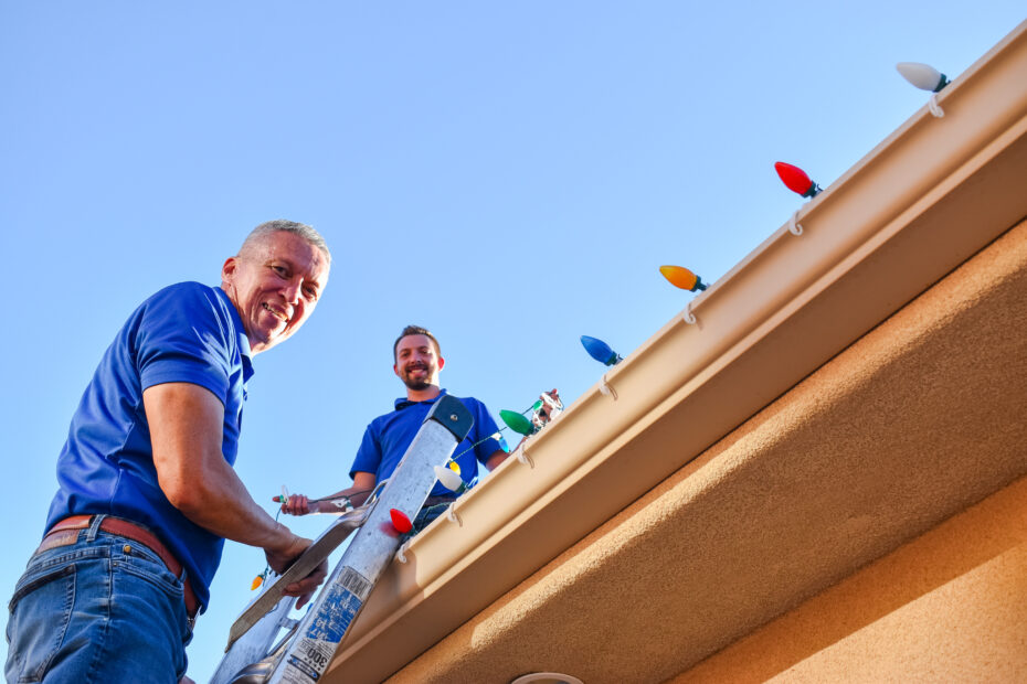 Ryan and Stuart from DSS smiling on the roof of a home while installing lights